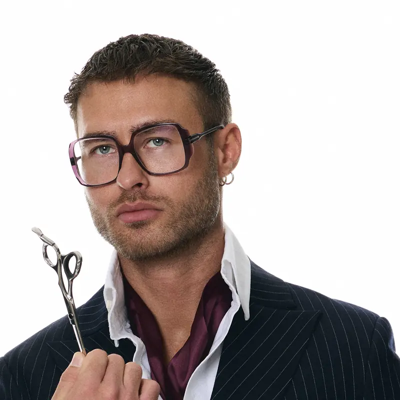 Dawid Krynicki in a double-breasted suit and neckerchief, scissors in hand