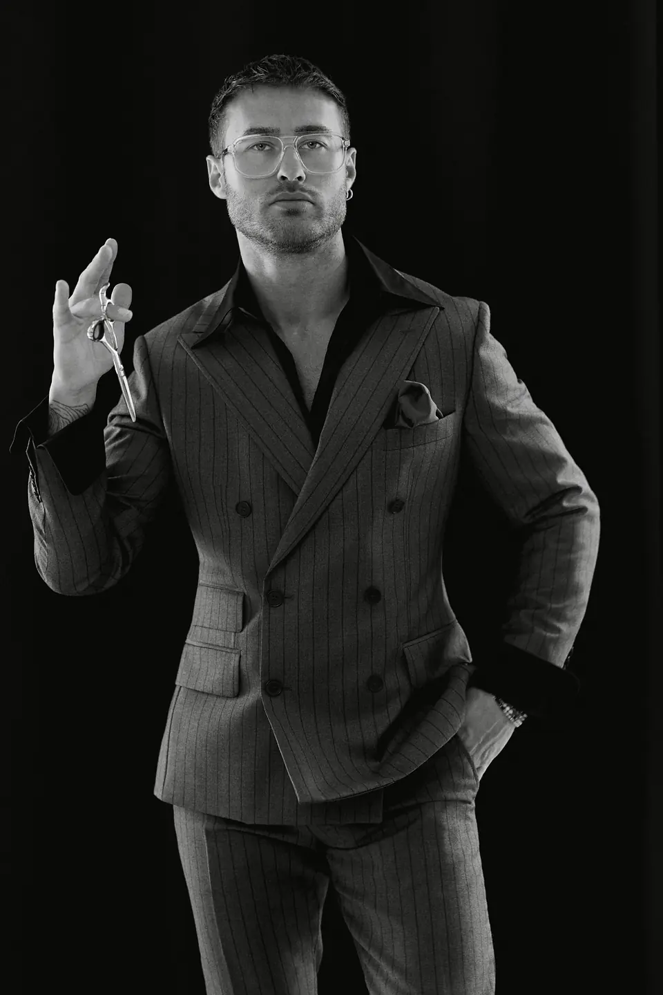 Dawid Krynicki in a double-breasted suit raises his scissors, black-and-white photo