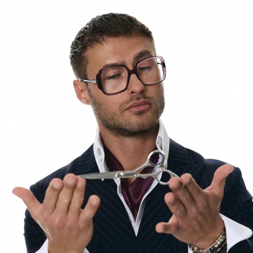 Dawid Krynicki holds hairdressing scissors above open palms