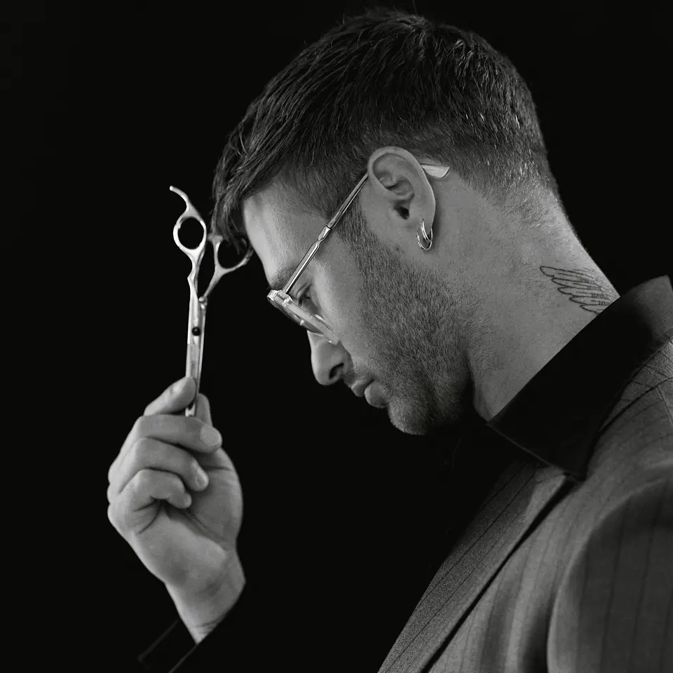 Dawid Krynicki in profile, scissors at his forehead, black-and-white photo