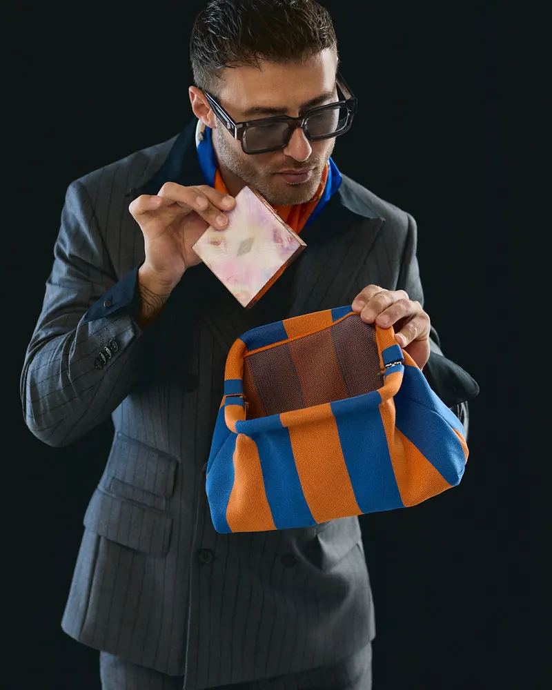Dawid Krynicki takes a sheet of paper out of a colourful striped bag