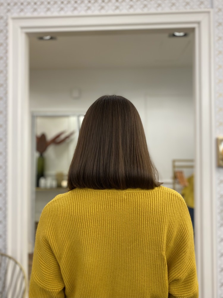 Client with a brown bob in a yellow jumper, seen from behind